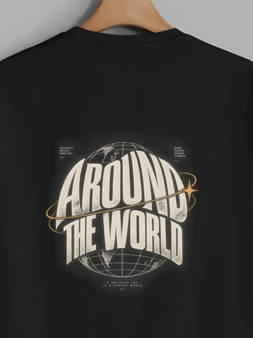 A black short-sleeve t-shirt hanging on a wooden hanger against a solid gray background. The back of the shirt features a large graphic print with the words 'AROUND THE WORLD' in a stylized white and gold font, surrounding a globe illustration.