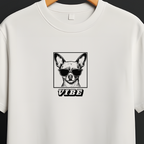 A white short-sleeve crewneck t-shirt hanging on a wooden hanger from a black clothing rack, featuring a black graphic of a dog wearing sunglasses with the word 'VIBE' underneath.