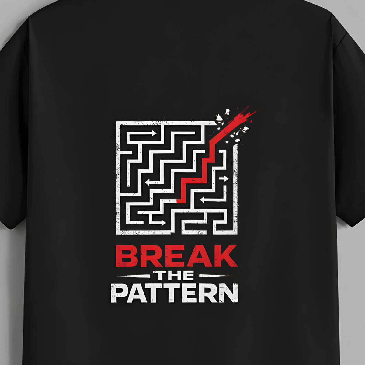 A black short-sleeve t-shirt hanging on a wooden hanger against a solid gray background. The back of the shirt features a graphic print with a white maze, a red checkmark, and the text 'BREAK THE PATTERN' in red and white.