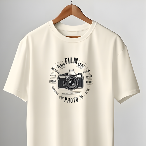 An off-white short-sleeve t-shirt with a black vintage film camera graphic and circular text on the chest, hanging on a wooden hanger from a clothing rack in front of a gray wall and white door.