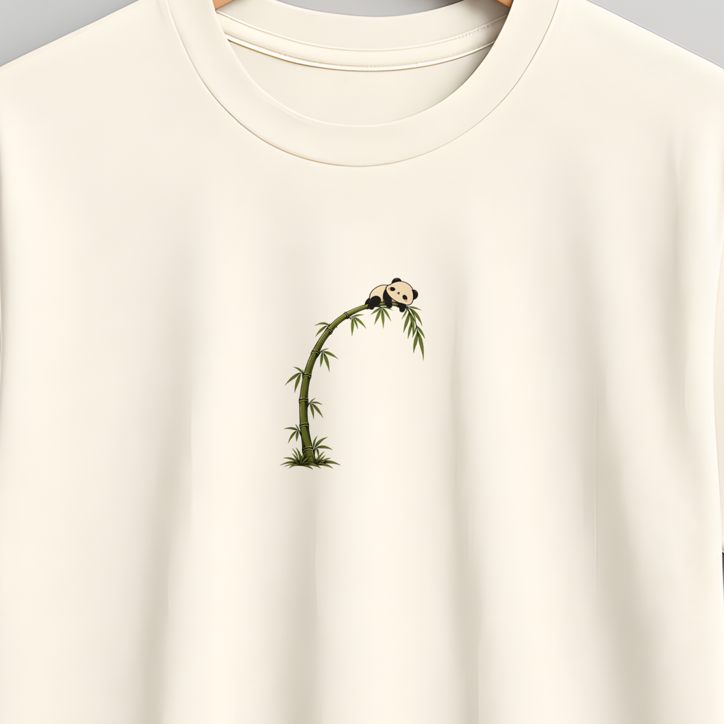 An off-white short-sleeve crewneck t-shirt hanging on a wooden hanger against a neutral gray background. The shirt features a small graphic print on the left chest depicting a green vine with tiny white flowers.