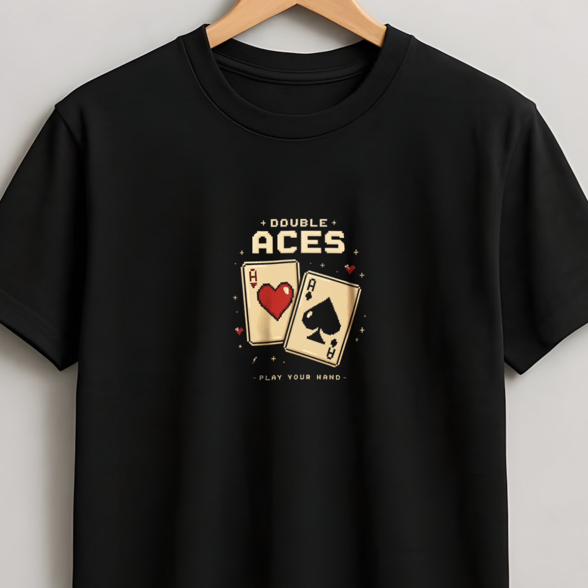 A black short-sleeve crewneck t-shirt hanging on a wooden hanger against a light gray wall. The shirt features a graphic print on the chest depicting two playing cards, an Ace of Hearts and an Ace of Spades, with the text 'A BUNCH OF ACES' above and 'PLAY BACK GAME' below.