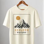 An off-white short-sleeve crewneck t-shirt hanging on a wooden hanger from a clothing rack. The shirt features a graphic print of a mountain under a yellow sun with the text 'EXPLORE BEYOND'.