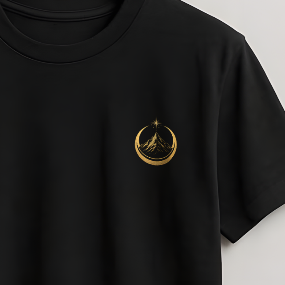 A black short-sleeve crewneck t-shirt hanging on a wooden hanger against a light gray wall. The shirt features a small gold circular logo on the left chest containing a stylized figure.