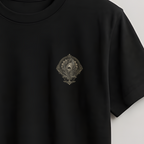 A black short-sleeve crewneck t-shirt hanging on a wooden hanger against a light gray wall. The shirt features a small, dark embroidered crest logo on the left chest.