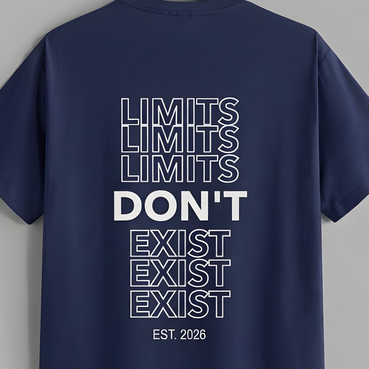 A navy blue short-sleeve t-shirt hanging on a wooden hanger against a solid gray background. The back of the shirt features a white graphic text design that reads 'LIMITS LIMITS LIMITS DON'T EXIST EST.