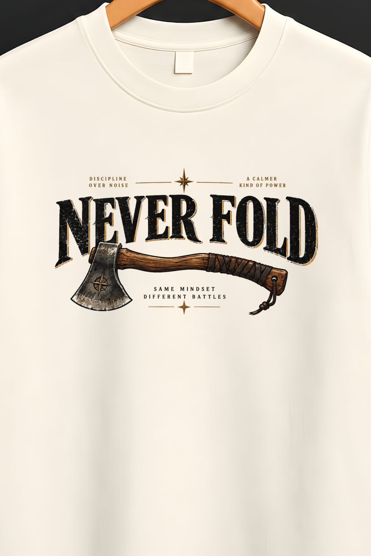 An off-white short-sleeve t-shirt hanging on a wooden hanger against a dark background. The shirt features a graphic print on the front with the text 'NEVER FOLD' and an illustration of a camp axe.