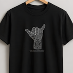 A black short-sleeve crewneck t-shirt hanging on a wooden hanger against a light gray wall. The shirt features a white graphic of a hand sign with intricate patterns inside, and the text 'THE SHIT IS GETTING EASY' printed below it.