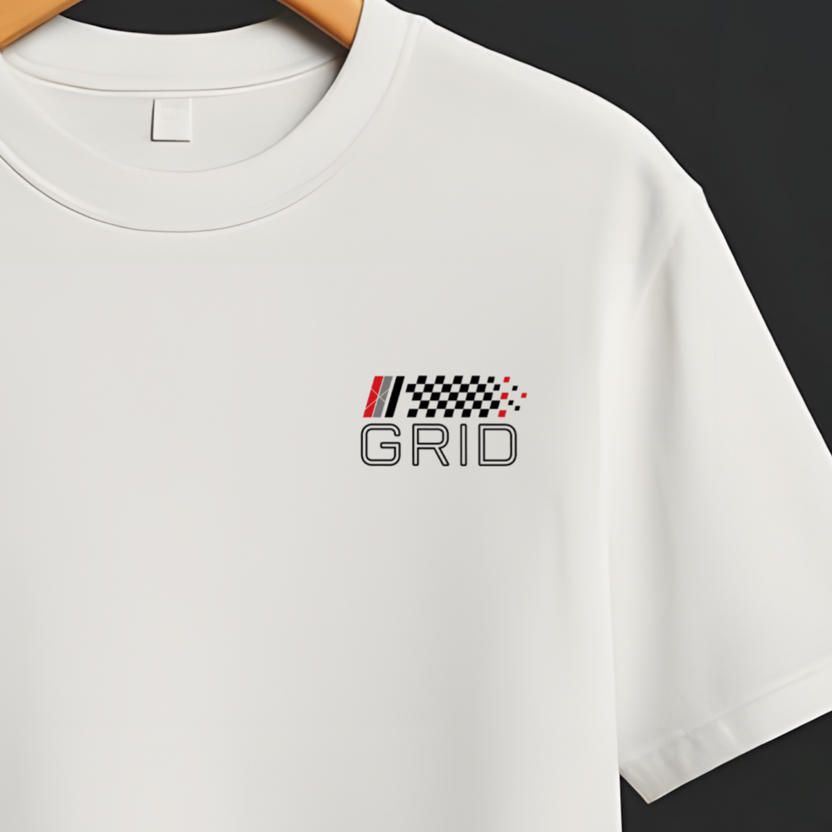 A white short-sleeve crewneck t-shirt hanging on a wooden hanger from a black rail, featuring a small 'GRID' racing logo with a checkered flag motif on the left chest.