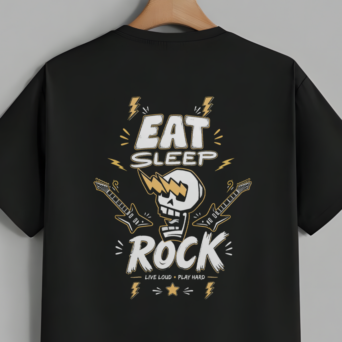 A black short-sleeve t-shirt hanging on a wooden hanger against a solid gray background, featuring a large graphic print on the back with the words 'EAT SLEEP ROCK' and a skull playing a guitar.